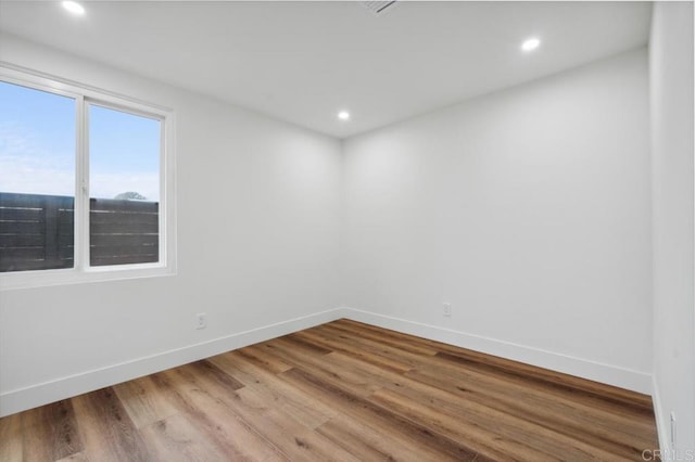 spare room featuring recessed lighting, baseboards, and wood finished floors