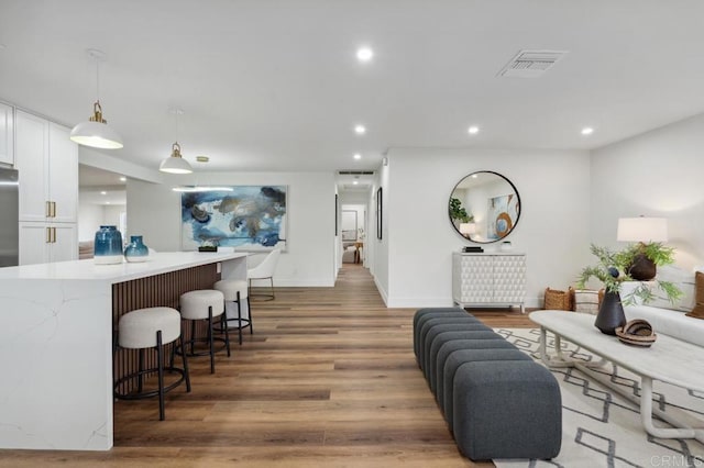 living area featuring recessed lighting, visible vents, baseboards, and wood finished floors