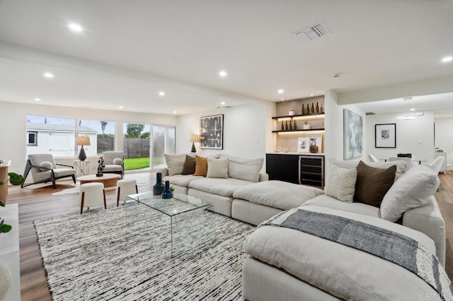 living area featuring wood finished floors, a dry bar, recessed lighting, and beverage cooler