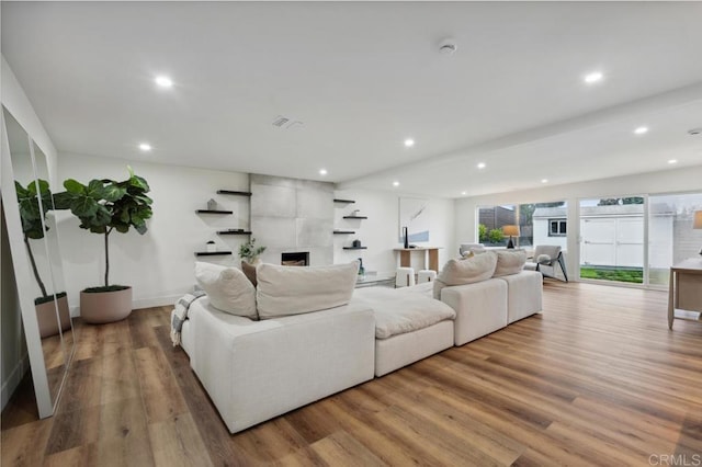 living area with recessed lighting, wood finished floors, and a large fireplace