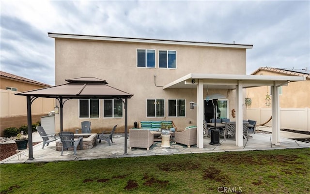 back of property with stucco siding, an outdoor living space with a fire pit, a patio, and fence