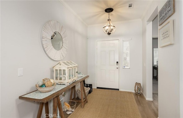 entrance foyer with visible vents, wood finished floors, baseboards, and ornamental molding