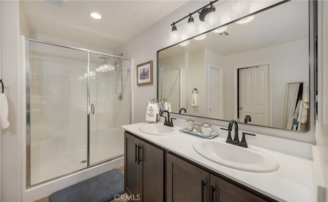 bathroom with a sink, visible vents, double vanity, and a shower stall