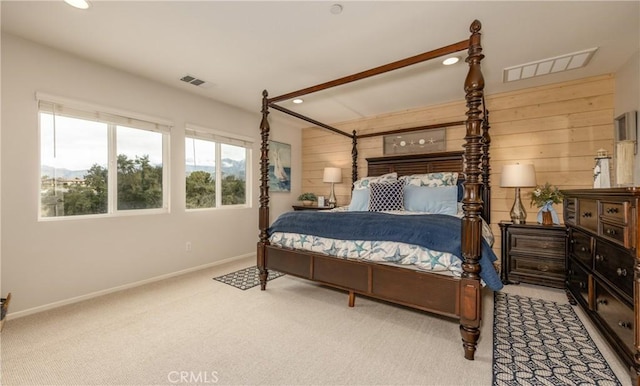 bedroom featuring carpet, visible vents, wood walls, and baseboards