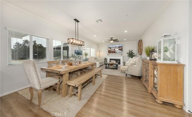 dining room with visible vents, crown molding, baseboards, light wood-style flooring, and a fireplace