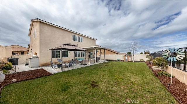 rear view of house with stucco siding, a yard, a fenced backyard, and a patio area