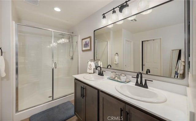 full bathroom with double vanity, visible vents, a shower stall, and a sink