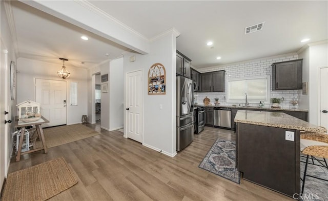 244 Country Club Dr, Calimesa, CA 92320 - kitchen featuring appliances with stainless steel finishes, ornamental molding, light wood finished floors, light stone countertops, and tasteful backsplash