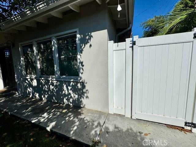 view of property exterior featuring stucco siding, fence, and a gate