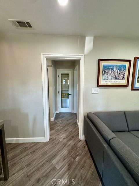 hall featuring visible vents, baseboards, and wood finished floors