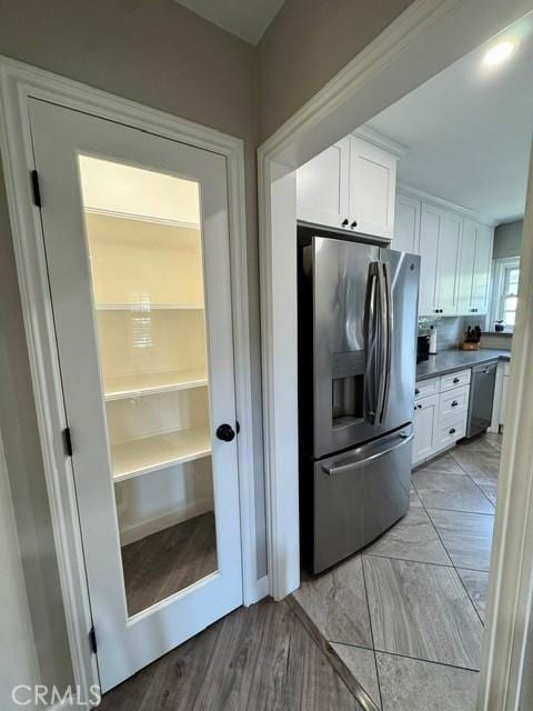 kitchen with stainless steel appliances, dark countertops, and white cabinetry