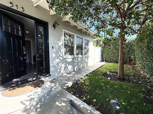 entrance to property featuring stucco siding and fence