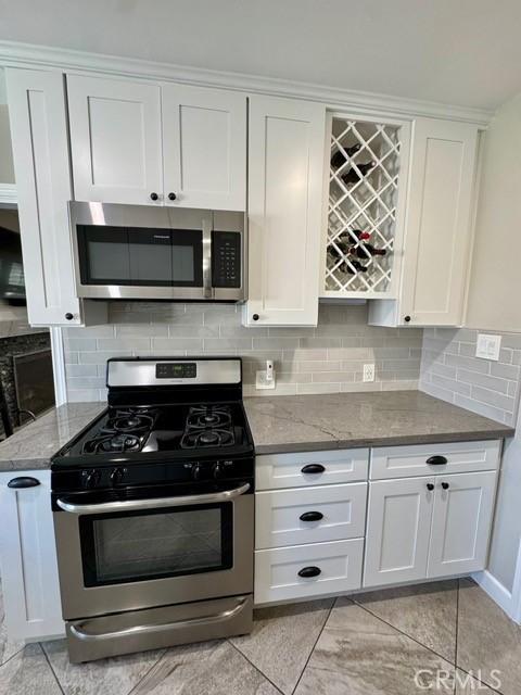 513 W Commonwealth Ave, Alhambra, CA 91801 - kitchen featuring stone countertops, white cabinetry, backsplash, and stainless steel appliances