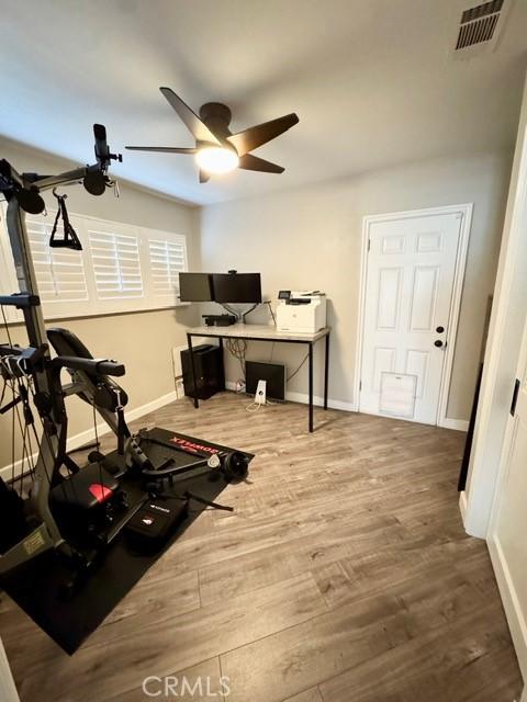 workout room with a ceiling fan, wood finished floors, visible vents, and baseboards