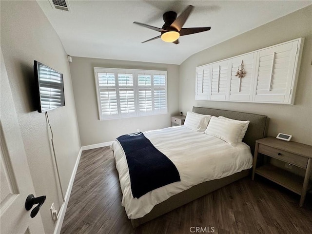 bedroom with visible vents, baseboards, vaulted ceiling, dark wood-style floors, and a ceiling fan