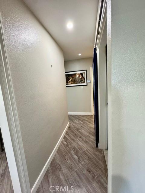 corridor featuring baseboards and wood finished floors