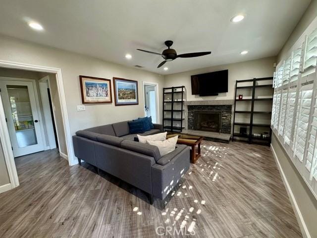 living area with recessed lighting, baseboards, wood finished floors, and a fireplace