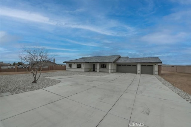 view of front of house featuring a garage, concrete driveway, stucco siding, and fence