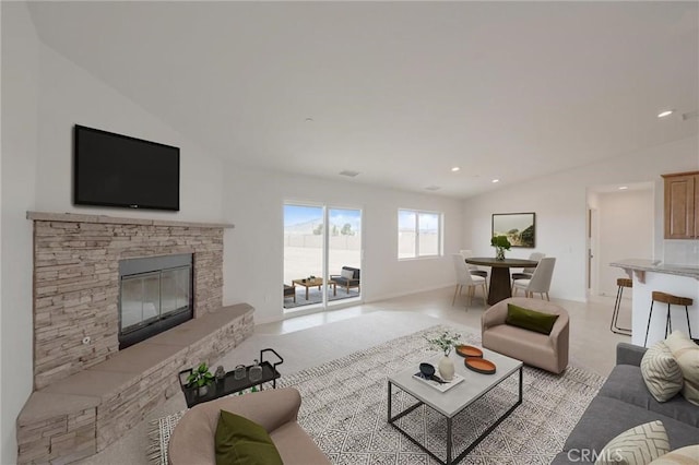 living area with recessed lighting, a stone fireplace, and vaulted ceiling