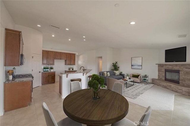 dining room with recessed lighting, visible vents, a stone fireplace, and light tile patterned floors