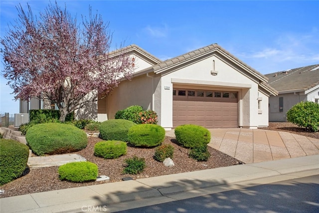 view of front of property with a tile roof, concrete driveway, an attached garage, and stucco siding