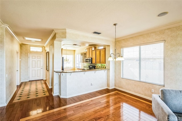 kitchen featuring visible vents, ornamental molding, appliances with stainless steel finishes, and hardwood / wood-style floors