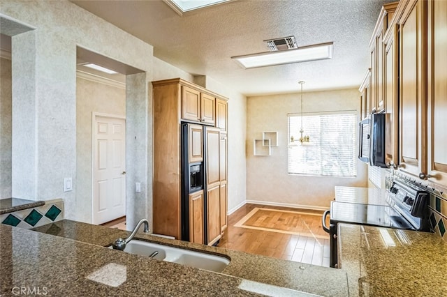 kitchen with light wood-type flooring, visible vents, a sink, stainless steel microwave, and black electric range