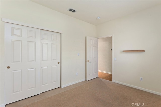 unfurnished bedroom featuring a closet, visible vents, baseboards, and carpet floors