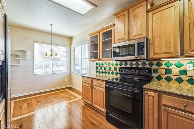 kitchen featuring a notable chandelier, stainless steel microwave, backsplash, black range with electric cooktop, and light wood-style floors