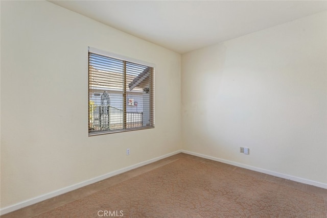 unfurnished room featuring light carpet and baseboards