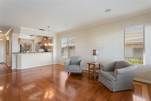 sitting room featuring crown molding, light wood finished floors, and a chandelier