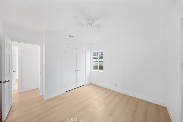 unfurnished bedroom featuring visible vents, baseboards, light wood-style floors, a closet, and a ceiling fan