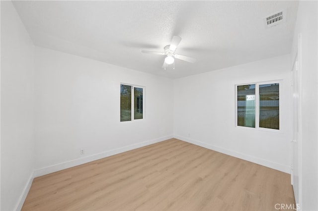 unfurnished room with a ceiling fan, light wood-style floors, visible vents, and baseboards