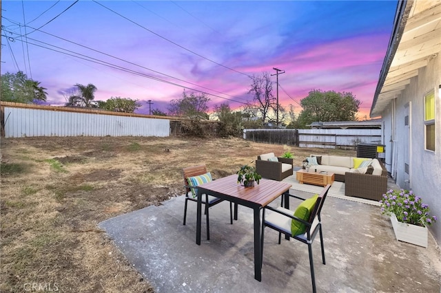 patio terrace at dusk featuring a fenced backyard and an outdoor hangout area