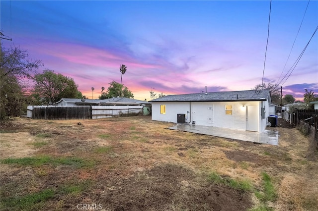 back of property at dusk featuring central AC unit, fence, and a patio