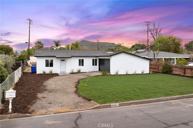 ranch-style house with a front yard, fence, and stucco siding