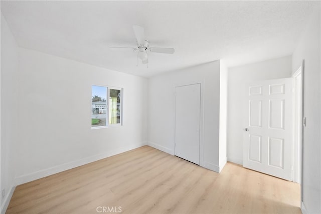 unfurnished bedroom featuring a closet, baseboards, wood finished floors, and a ceiling fan