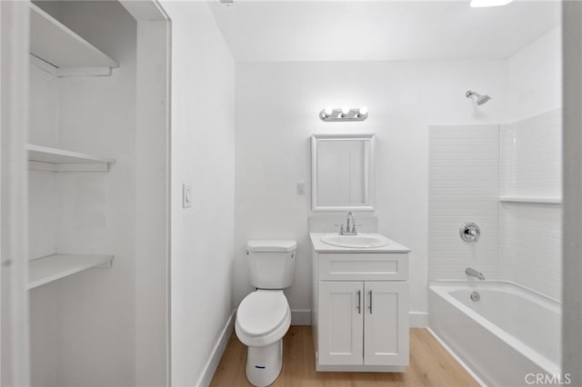 full bath with baseboards, toilet, vanity, wood finished floors, and washtub / shower combination