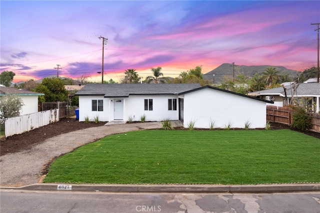 ranch-style house featuring a front lawn, fence, and stucco siding