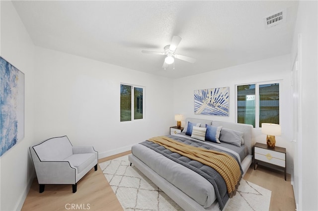 bedroom featuring visible vents, multiple windows, ceiling fan, and light wood finished floors