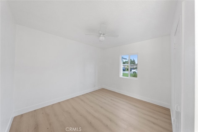 empty room with a ceiling fan, light wood-type flooring, and baseboards