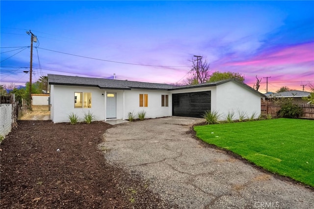 mid-century home featuring stucco siding, driveway, a garage, and fence