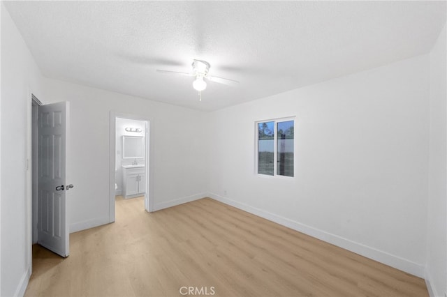 unfurnished bedroom featuring light wood finished floors, a textured ceiling, baseboards, and a ceiling fan