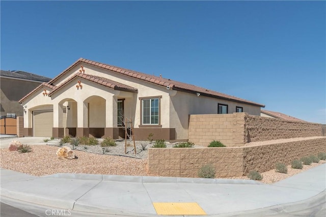 mediterranean / spanish house featuring fence, driveway, an attached garage, stucco siding, and a tile roof