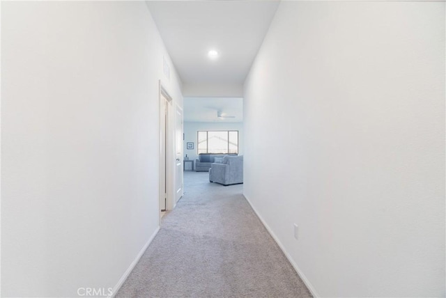 hallway featuring baseboards and light carpet