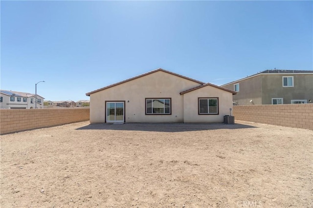 rear view of property featuring central air condition unit, stucco siding, and a fenced backyard