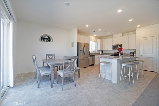 kitchen with a kitchen island, appliances with stainless steel finishes, a breakfast bar area, and white cabinetry