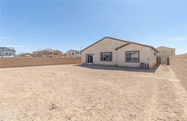 rear view of property with central air condition unit, a fenced backyard, and stucco siding