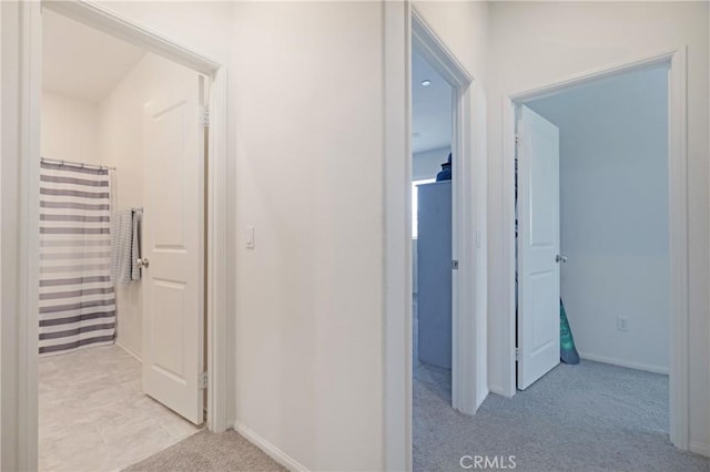 hall featuring light colored carpet and baseboards