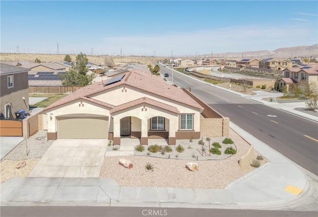 view of front of property featuring fence, driveway, stucco siding, a garage, and a residential view